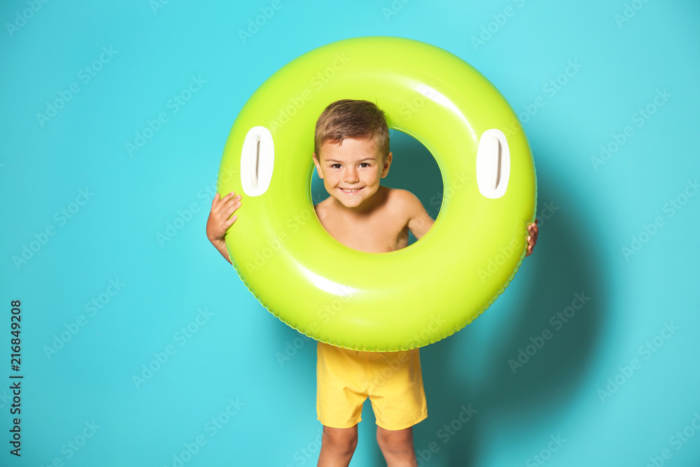 Fototapeta premium Cute little boy with inflatable ring on color background
