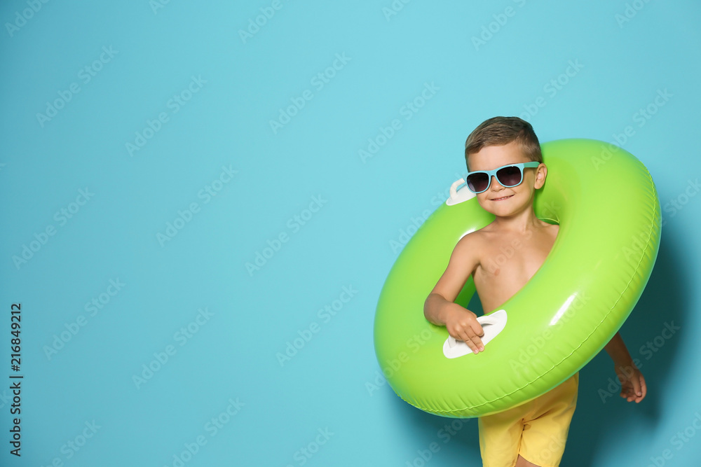 Fototapeta premium Cute little boy with inflatable ring on color background