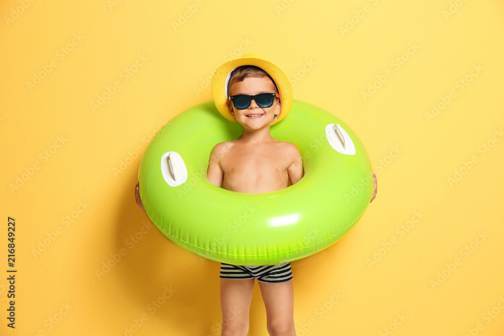 Fototapeta premium Cute little boy with inflatable ring on color background
