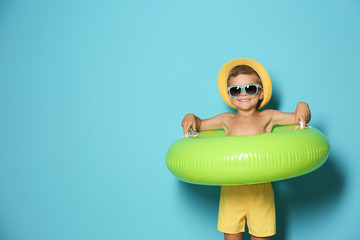 Cute little boy with inflatable ring on color background