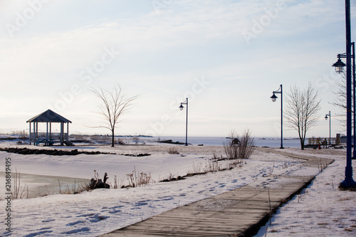 Wood path walkway to pavilion at frozen lake shore on a calm winter morning