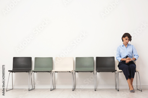 Young woman sitting on chair and waiting for job interview