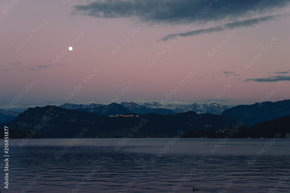 Night summer view with moon light on Alps mountains lake and Pilatus mountain, city glows, travel and vacation in Europe, embankment, Luzern, Switzerland Night summer view with moon light on Alps mountains lake and Pilatus mountain, city glows, travel and vacation in Europe, embankment, Luzern, Switzerland