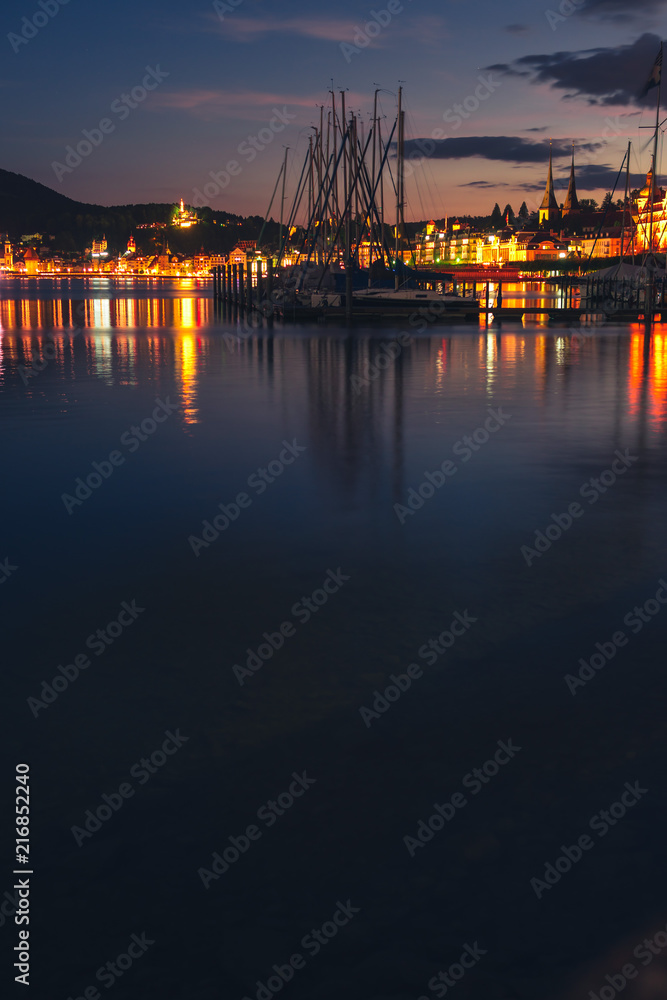 Night summer view on Alps mountains lake and Pilatus mountain, city glows, travel and vacation in Europe, embankment, Luzern, Switzerland, vertical photo