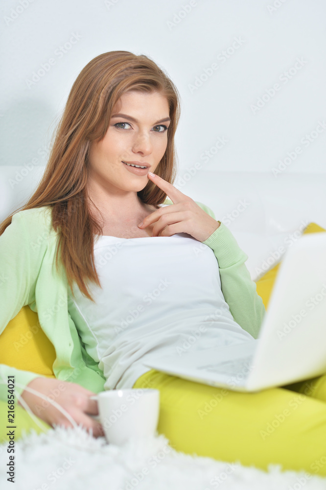 young beautiful woman relaxing in bed with laptop young beautiful woman relaxing in bed with laptop