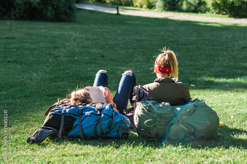 Relaxing summer day in a Danish park, young women travellers lounging on the grass. Concept of hygge.