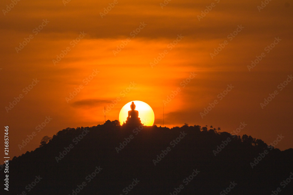 stunning red sky sunset the round sun is on the back of Phuket big Buddha on the high mountain .landmark of Phuket island can see isolated Phuket big Buddha from distance