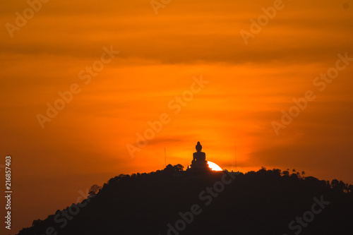 stunning red sky sunset the round sun is on the back of Phuket big Buddha on the high mountain .landmark of Phuket island can see isolated Phuket big Buddha from distance