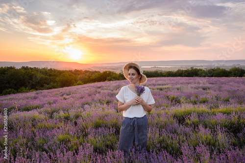 Fototapeta Naklejka Na Ścianę i Meble -  Beautiful woman in a field of lavender on sunset. Woman in amazing dress walk on the lavender field.