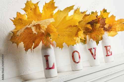 Yellow maple leaves in bottles with word love photo