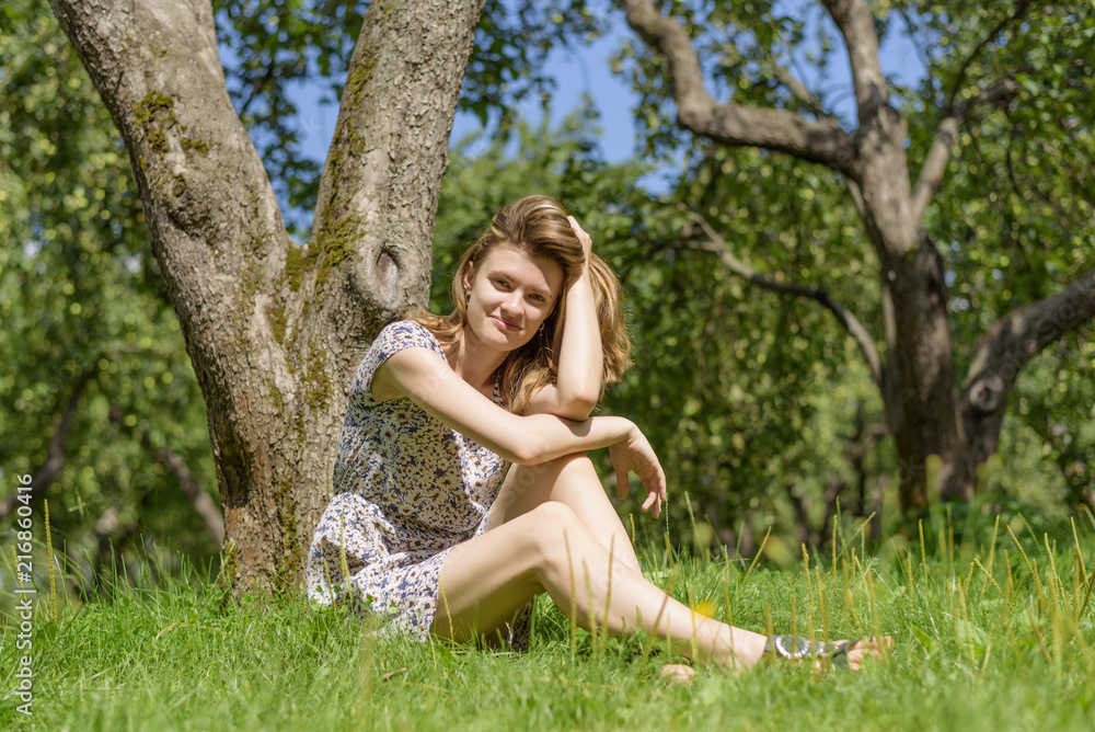 Young cute woman sits and rests in the garden under a tree Young cute woman sits and rests in the garden under a tree