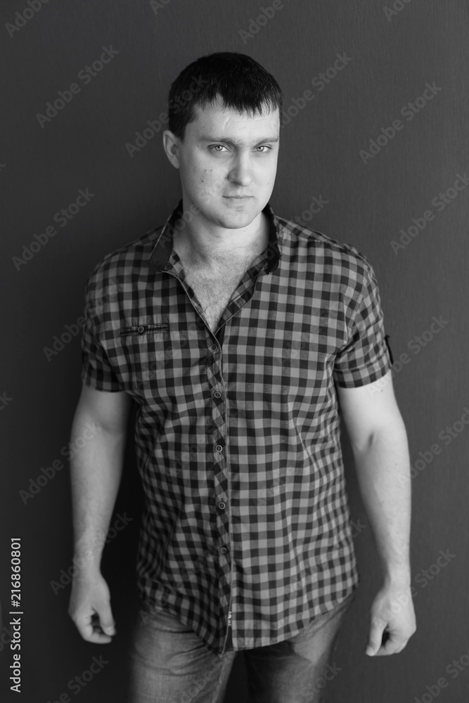 Naklejka premium young man in shirt and jeans. portrait of man. black and white male portrait photos