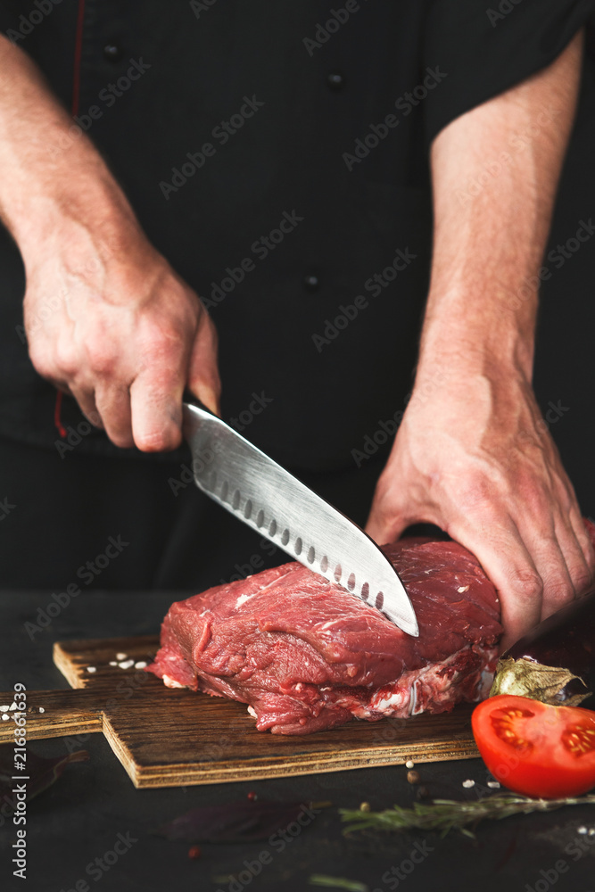 Chef cutting filet mignon on wooden board