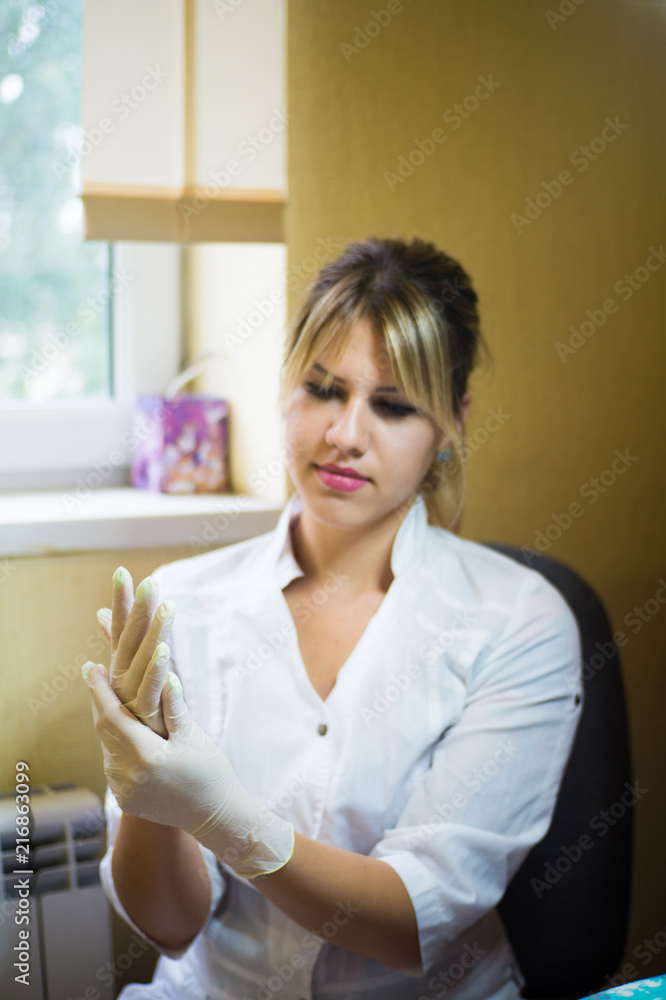 Master eyelash extension with medical tweezers in his hands and putting on disposable gloves in the beauty salon, facial cosmetology Master eyelash extension with medical tweezers in his hands and putting on disposable gloves in the beauty salon, facial cosmetology