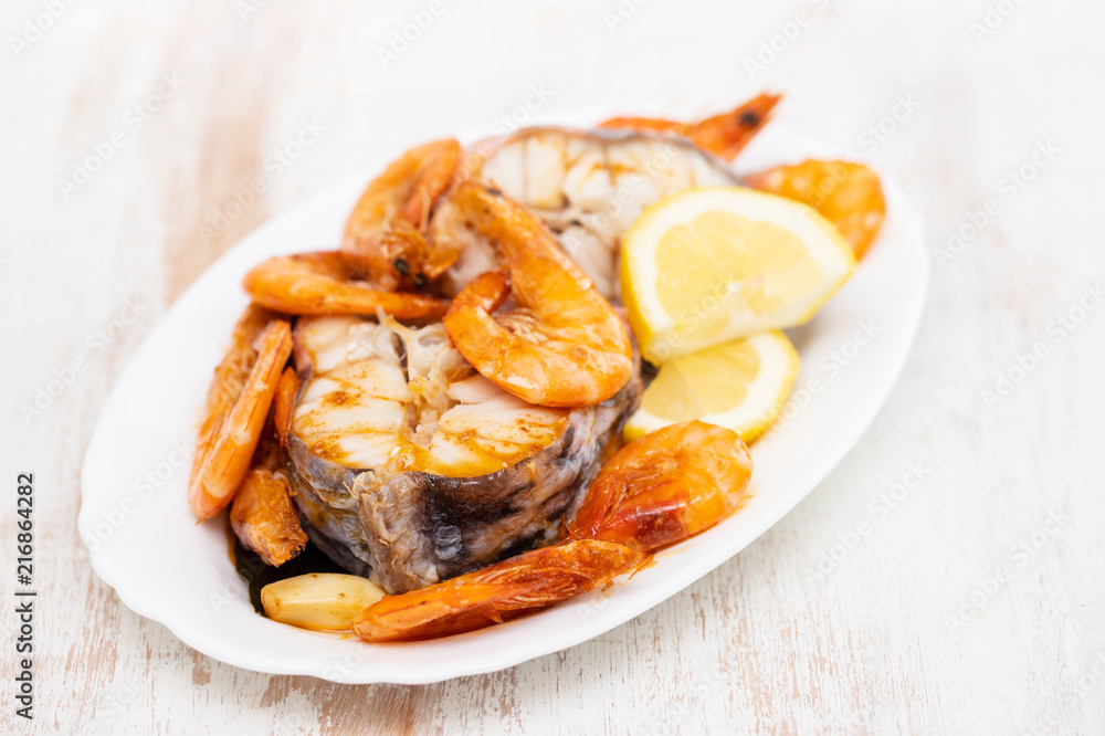 boiled fish with shrimps and lemon on white dish boiled fish with shrimps and lemon on white dish