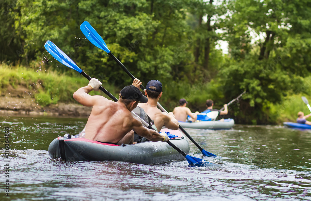 Kayaking on the river. Young men are rafting along a wild river in a kayak. Rowers with oars in the boat. Canoeing. A group of tourists are swimming along the river in a boat. Rowers rowing with oars
