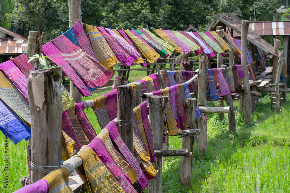 Hand woven clothes hang on wooden walkways in rice field at Sila Laeng, Pua District, Nan, Thailand