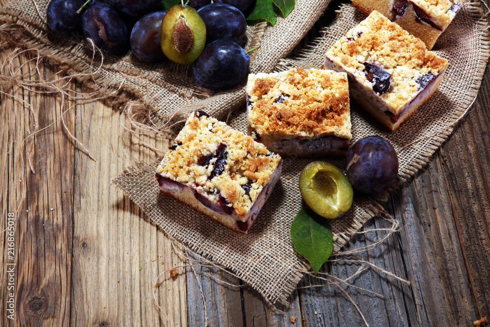 Rustic plum cake on wooden background with plums around. Rustic plum cake on wooden background with plums around.