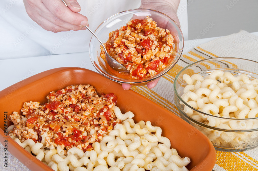 The cook prepares a meat casserole with pasta. The cook prepares a meat casserole with pasta.
