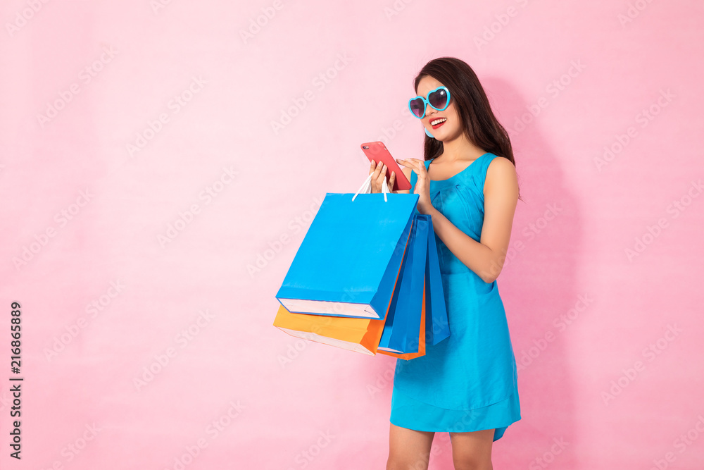 Happy Asian woman using cell phone on yellow background, autumn season,colorful shopping concept.