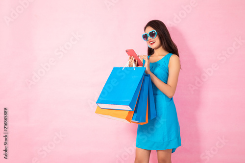 Happy Asian woman using cell phone on yellow background, autumn season,colorful shopping concept.