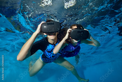 Happy family, mom and baby play in virtual reality helmets underwater in the pool. Close up. Shooting underwater. The horizontal orientation of the image