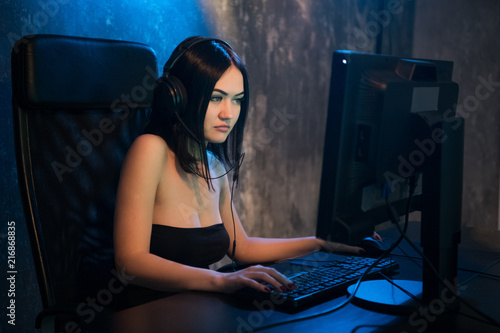 Young attractive woman playing video games on her computer wearing gaming headset.