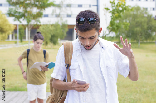 student with surprise expression watching mobile phone or smartphone