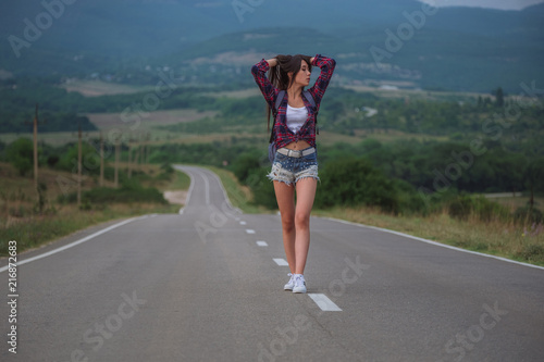 women is hailing a car on a road. Thumbing a ride. Outdoors vacation..