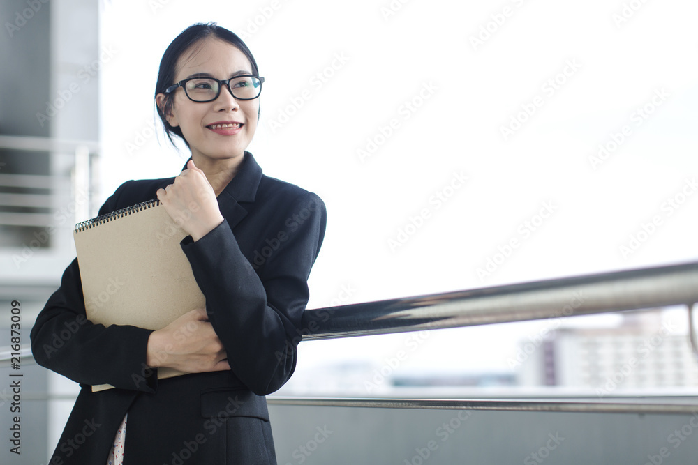Young Asian business woman wear suit holding file document, standing at office Young Asian business woman wear suit holding file document, standing at office