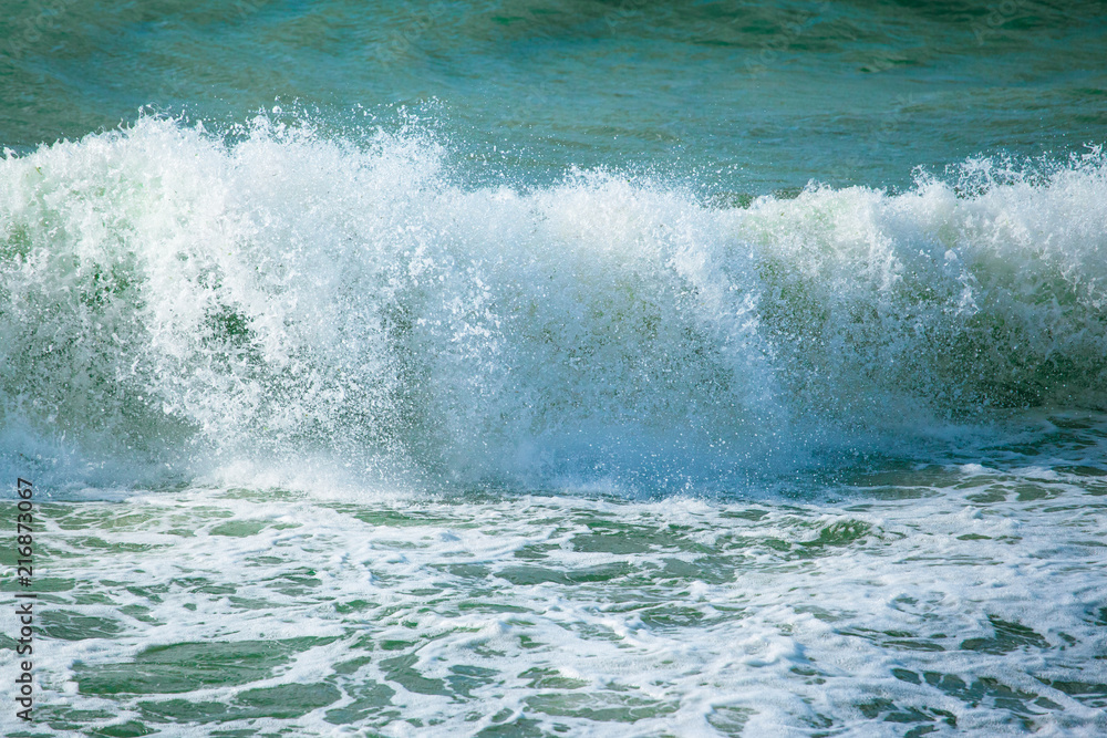 Fototapeta premium surface of turquoise ocean water with waves, spray and white foam