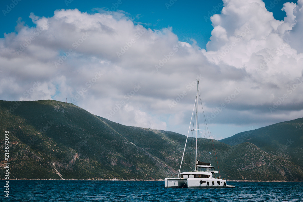 Catamaran ship in open sea near Fiskardo. Big clouds moving over the mountain shape of Ithaki island. Kefalonia Island Greece Catamaran ship in open sea near Fiskardo. Big clouds moving over the mountain shape of Ithaki island. Kefalonia Island Greece