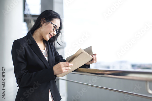 Young Asian business woman wear suit holding file document, standing at office