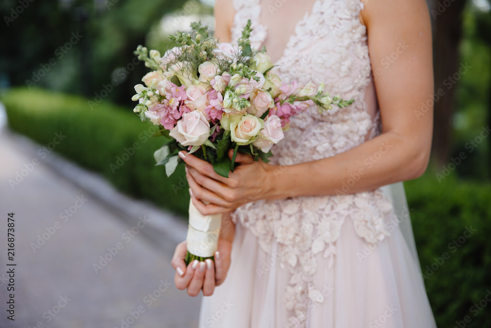 A close-up of a cropped wedding frame is a tender bouquet of roses in the hands of the bride. A girl in a wedding dress is holding flowers. A close-up of a cropped wedding frame is a tender bouquet of roses in the hands of the bride. A girl in a wedding dress is holding flowers.