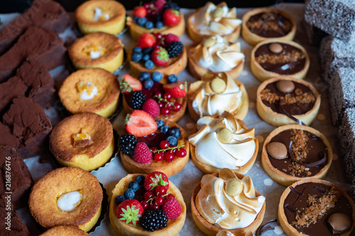 Assortment of delicious and colorful dessert, chocolate cakes, mixed berry tarts, Lemon Meringue Tarts, chocolate tarts made by pastry chef. All look very tasty and delightful. Natural light.