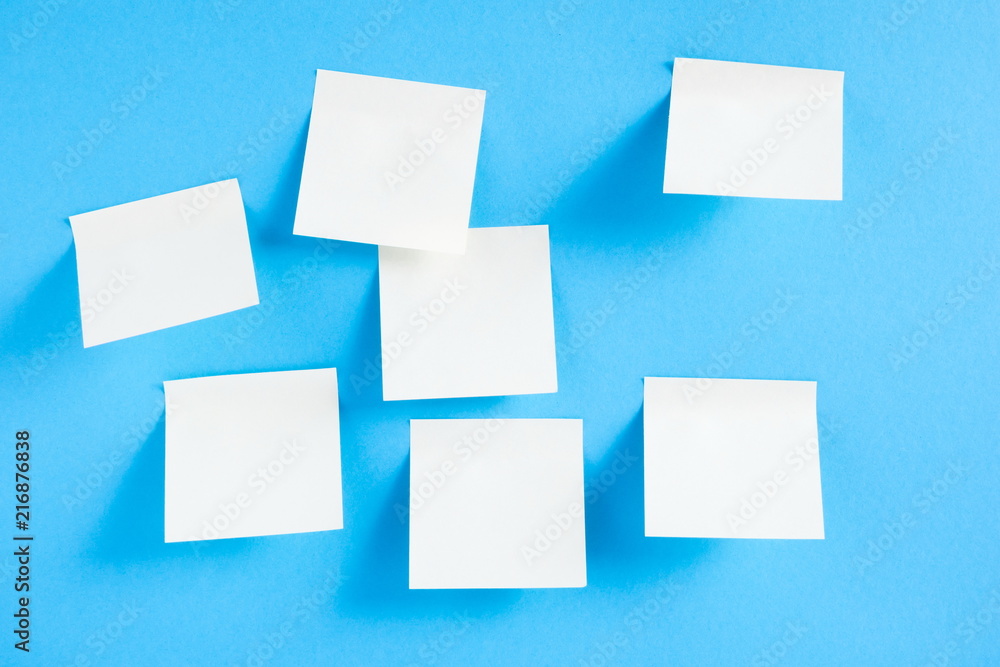 Blank white sticky notes on blue background, concept of business work. White memo stickers on blue wall. Mock-up Blank white sticky notes on blue background, concept of business work. White memo stickers on blue wall. Mock-up