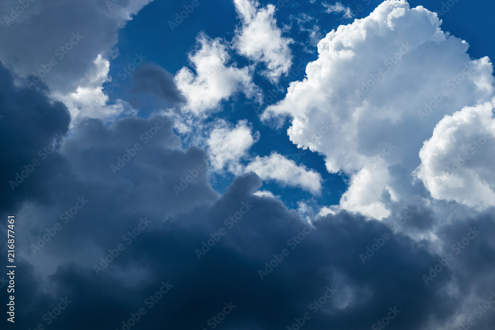 Obraz premium Texture of white and gray storm clouds on a blue sky in the sunlight, background