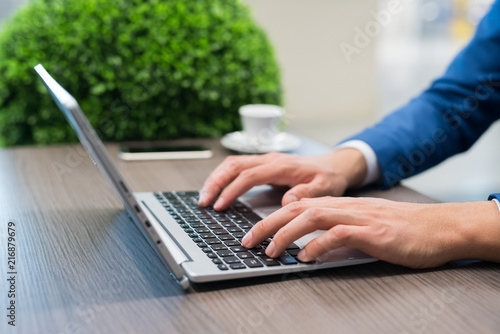 Detail of a businessman using a netbook in a cafe