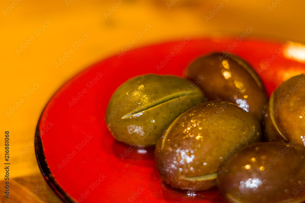 large marinated olives on a red saucer large marinated olives on a red saucer