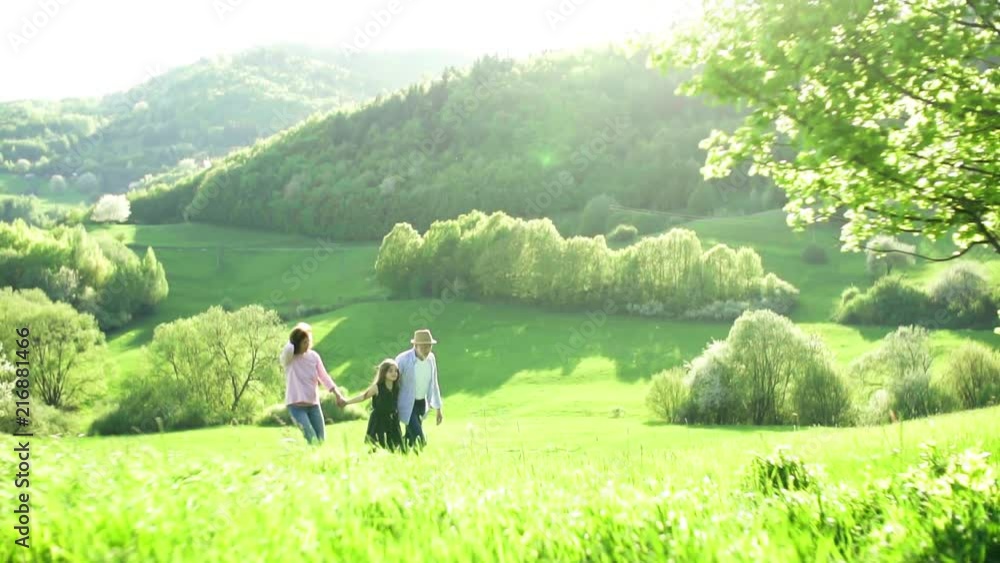 Senior couple with granddaughter outside in spring nature, running. Senior couple with granddaughter outside in spring nature, running.