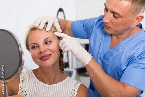 Man doctor is preparing female patient to procedure photo