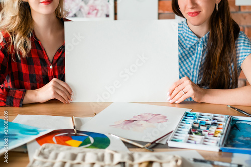 art painting leisure craft and hobby. drawing courses or classes. painter instruments and tools. women holding a blank sheet of white paper. empty space for advertisement.