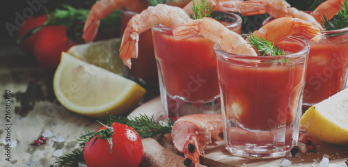 Shrimp cocktail in small glasses, cherry tomatoes, dill, parsley and lemon with salt and spices, selective focus and toned image photo