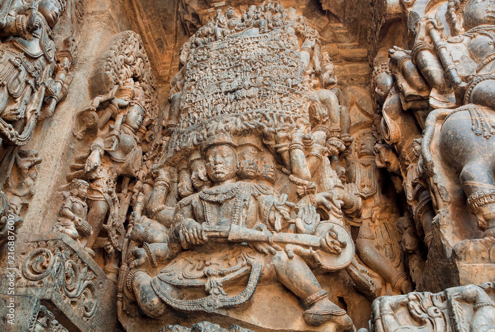 Magic gods and other sculptures on carved wall of 12th century historical Hoysaleswara Hindu temple, Halebidu, India.