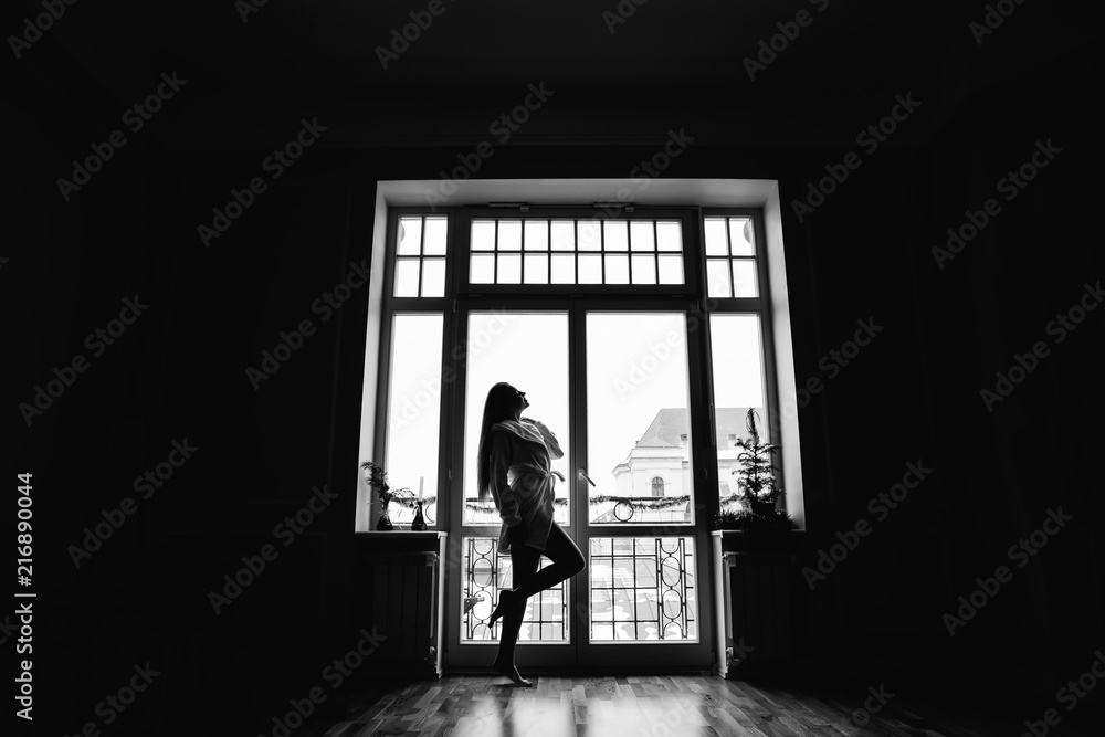 Silhouette of girl in the morning in full growth near window in Silhouette of girl in the morning in full growth near window in