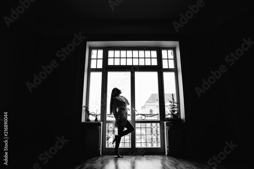 Silhouette of girl in the morning in full growth near window in © Ivan