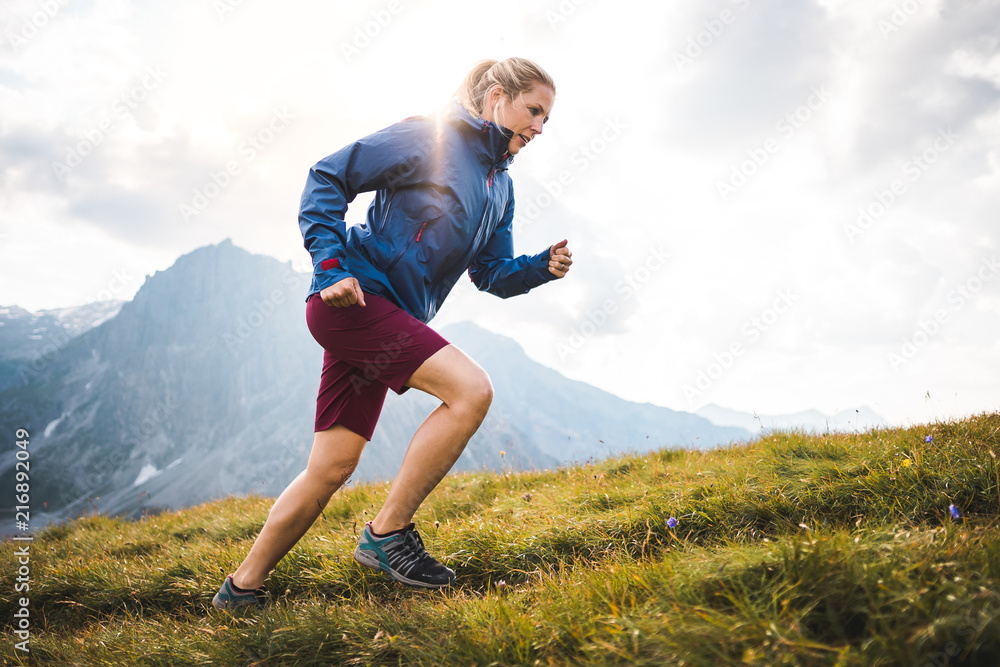 Sportive girl running on a trail through a beutiful Mountain Meadow in the Austrian Alps