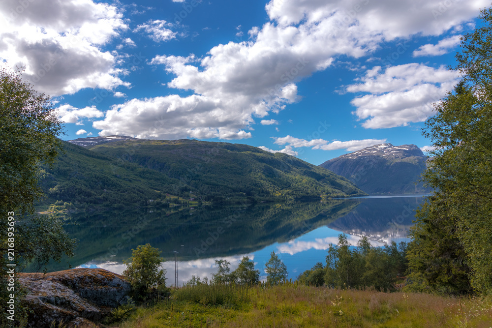 Obraz premium Norwegian mountain lake summer landscape. Clouds reflecting in the crystal clear water surface.