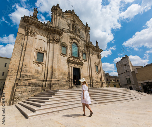 Beautiful girl in white dress walking next to historical builing in Matera, Basilicata, Italy.