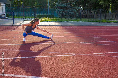 Attractive sporty woman stretching before race at the stadium, space for text